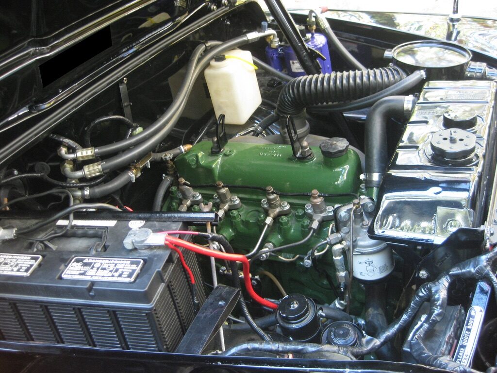 The engine bay with the diesel engine painted Austin green, surrounded by polished pipework and a period battery.